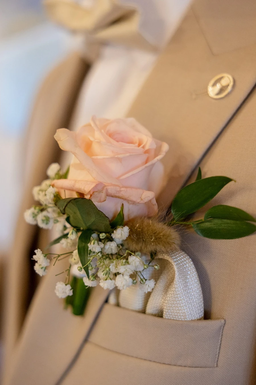 Anstecker aus apricotfarbener Rose, Schleierkraut und Eukalyptus am beigen Revers