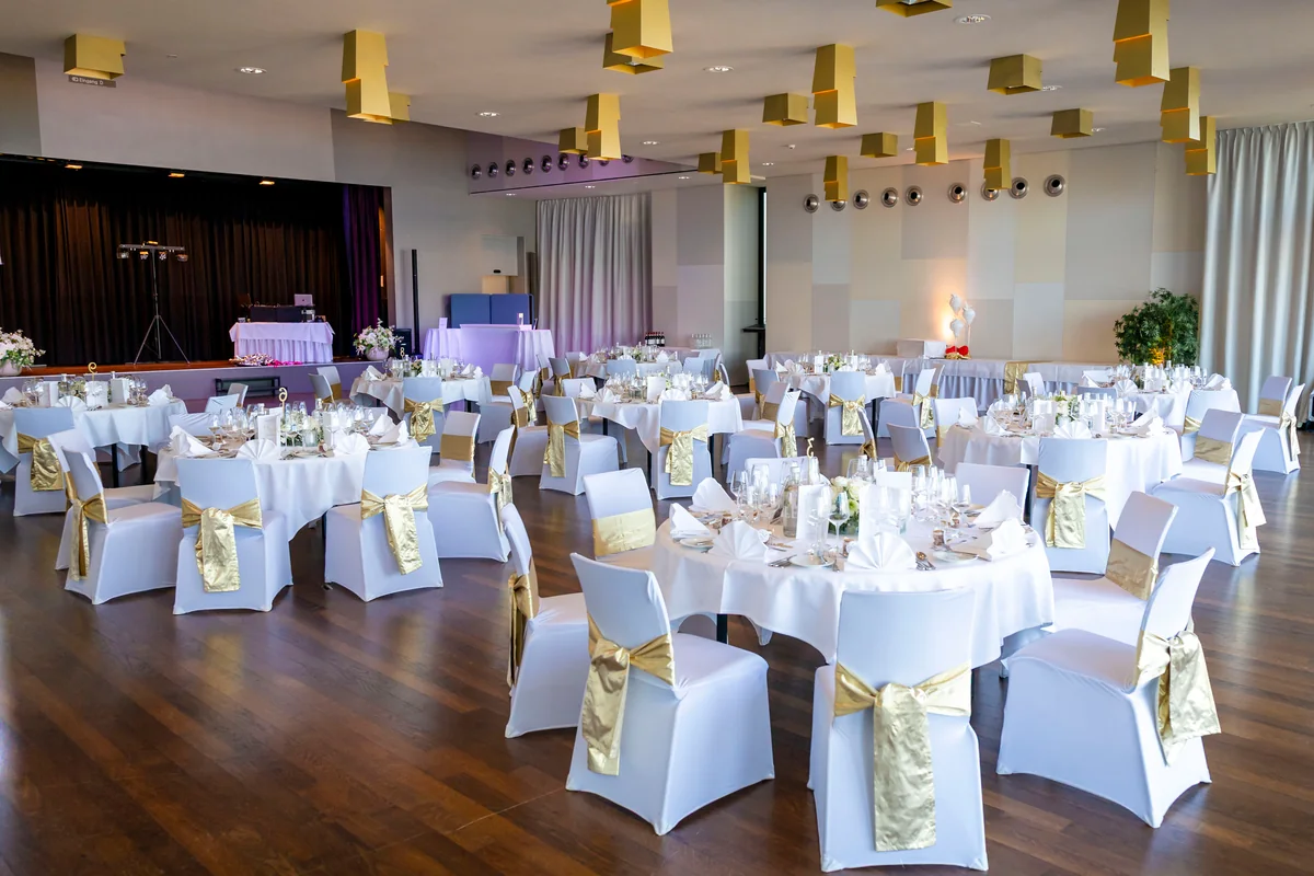 Belvoir Saal bei Tag mit goldenen Stuhlschleifen und der Bühne im Hintergrund