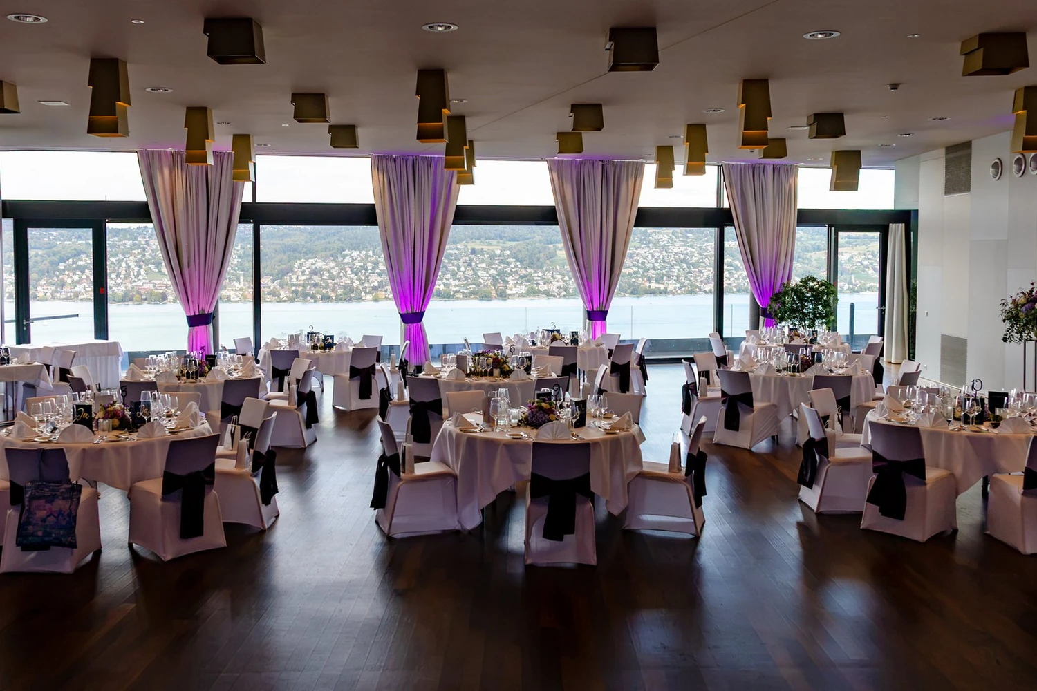 Belvoir Saal mit der Fensterfront zum Zürichsee, runde Tische und dunkles Parkett