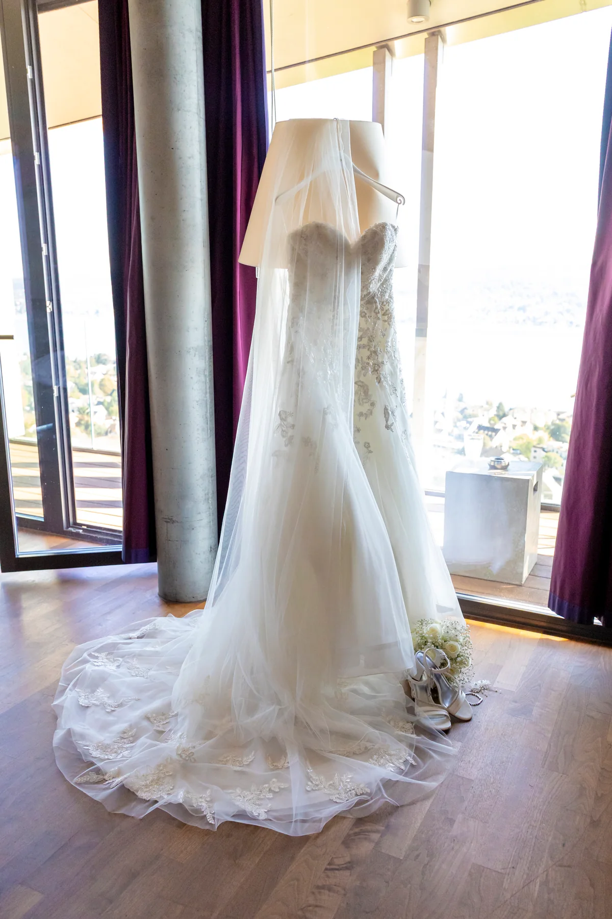 Hochzeitskleid hängt im Fenster des Hotelzimmers, dahinter der Zürichsee