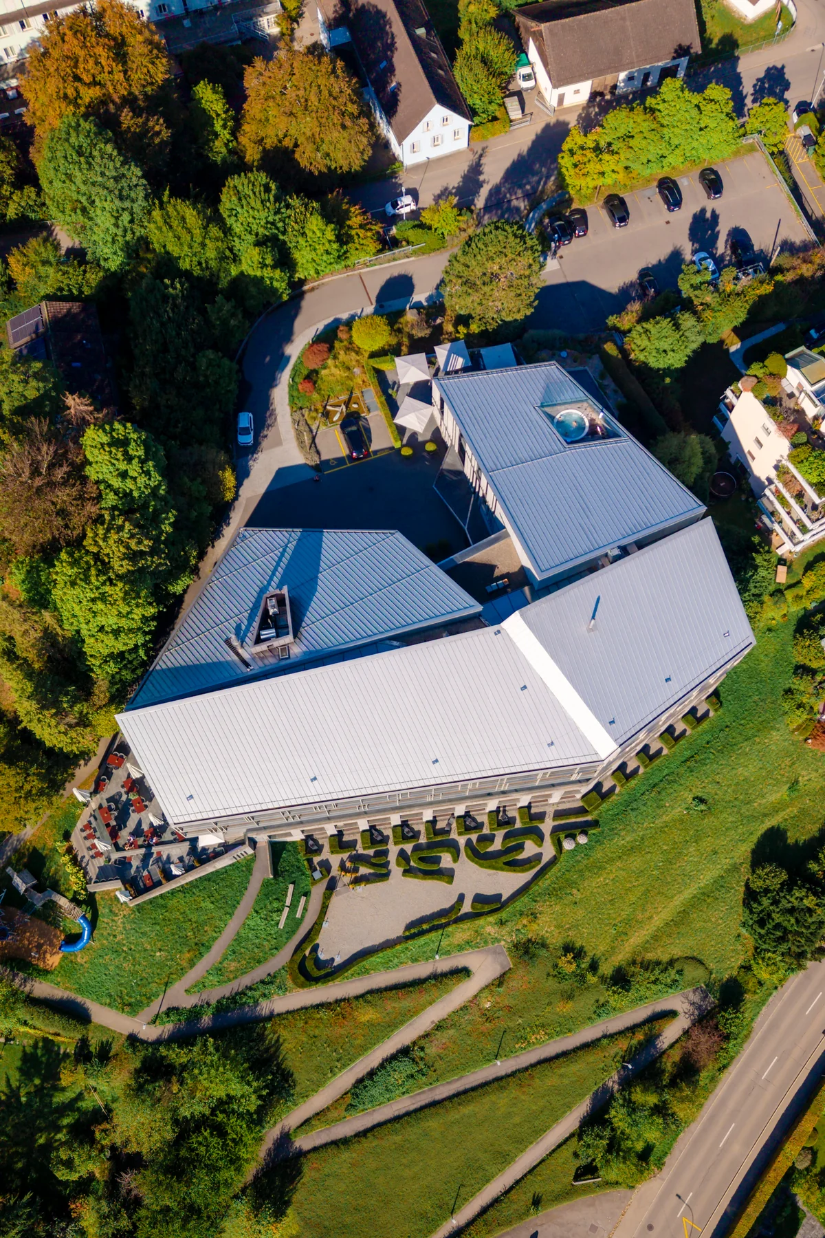 Luftaufnahme über dem Dach des Hotels mit den Gartenwegen darunter