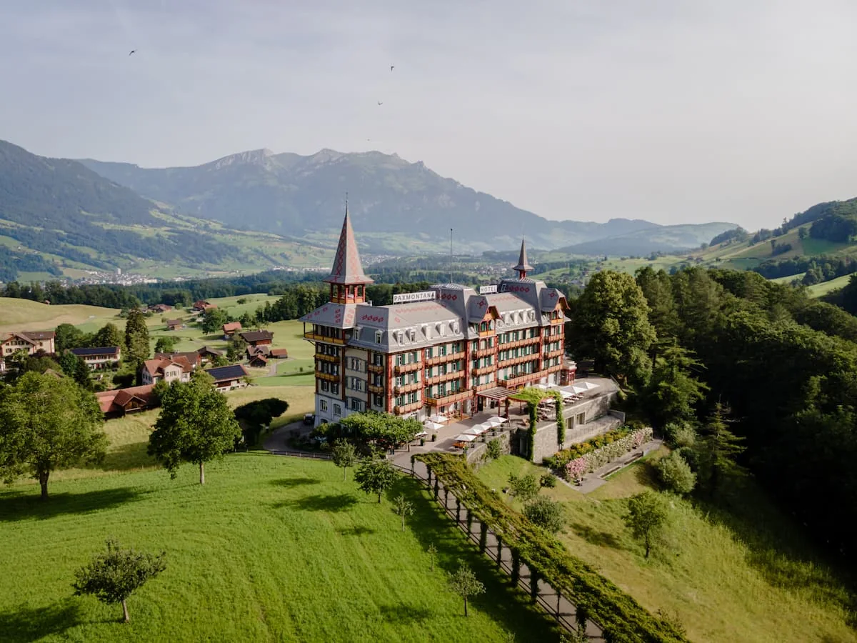 Das Jugendstilhotel Paxmontana in Flüeli-Ranft aus der Luft, dahinter die Berge