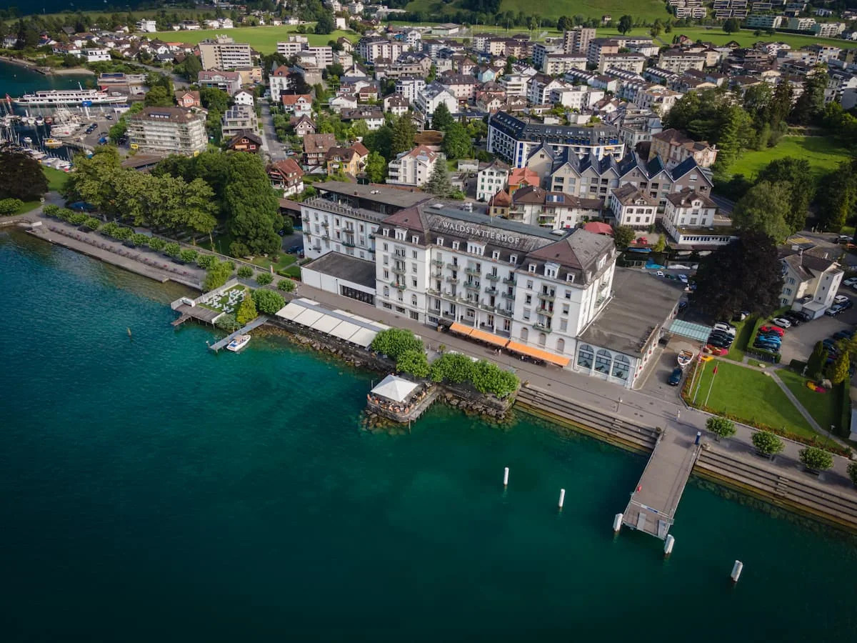 Das Seehotel Waldstätterhof in Brunnen am Vierwaldstättersee von oben, davor der Steg und türkises Wasser