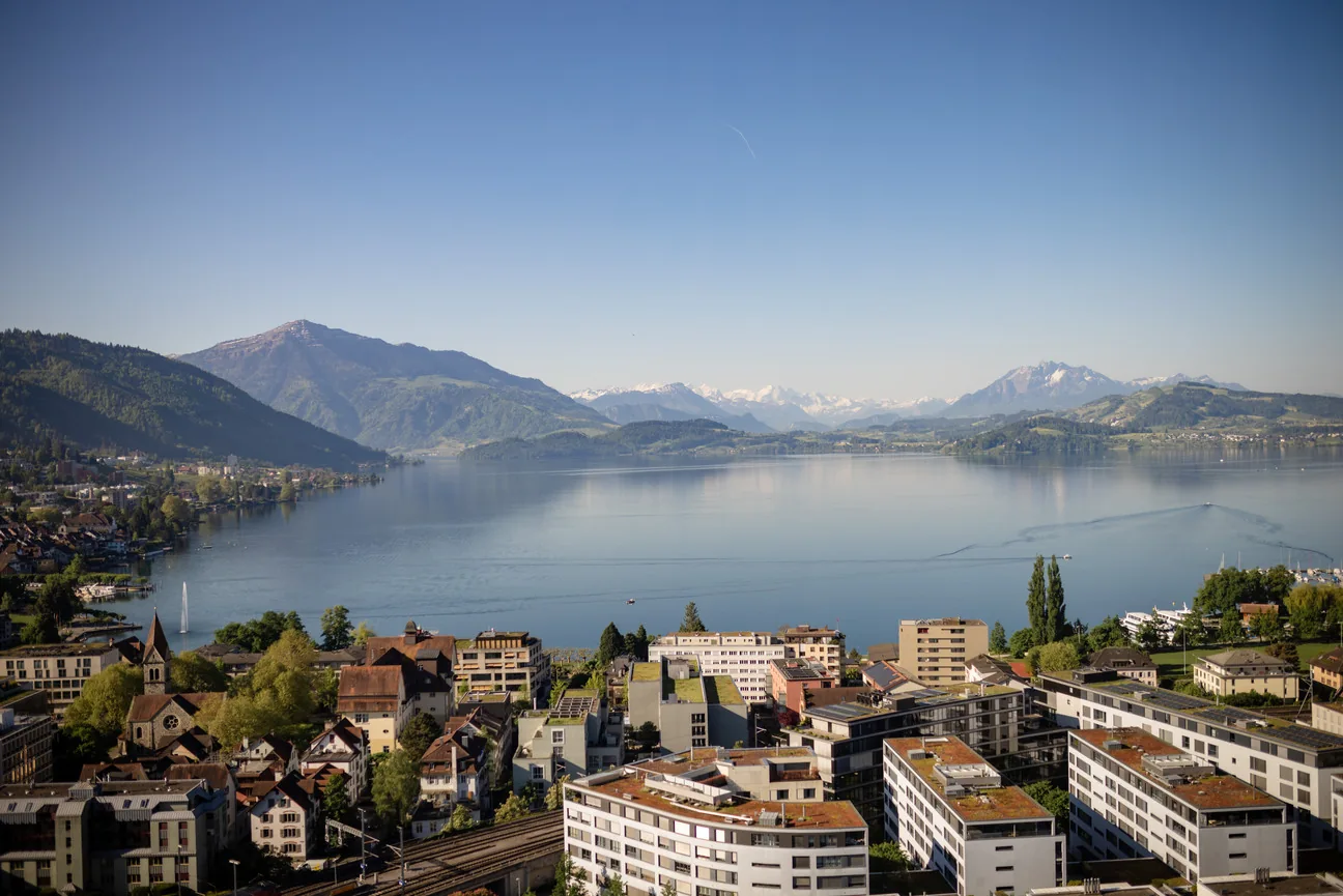 Die Stadt Zug und der Zugersee im Morgenlicht, dahinter die Berge