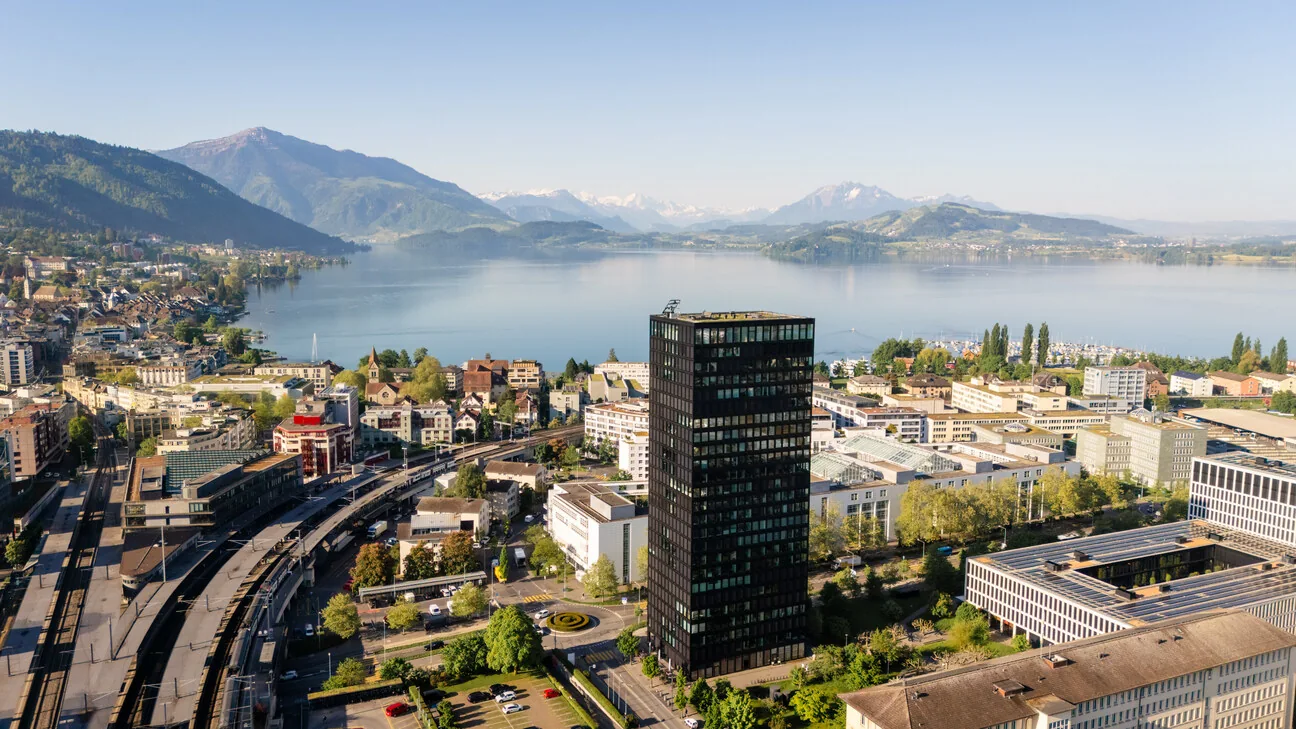 Weitwinkel über Zug: der Park Tower, die Stadt, der Zugersee und die Alpen dahinter