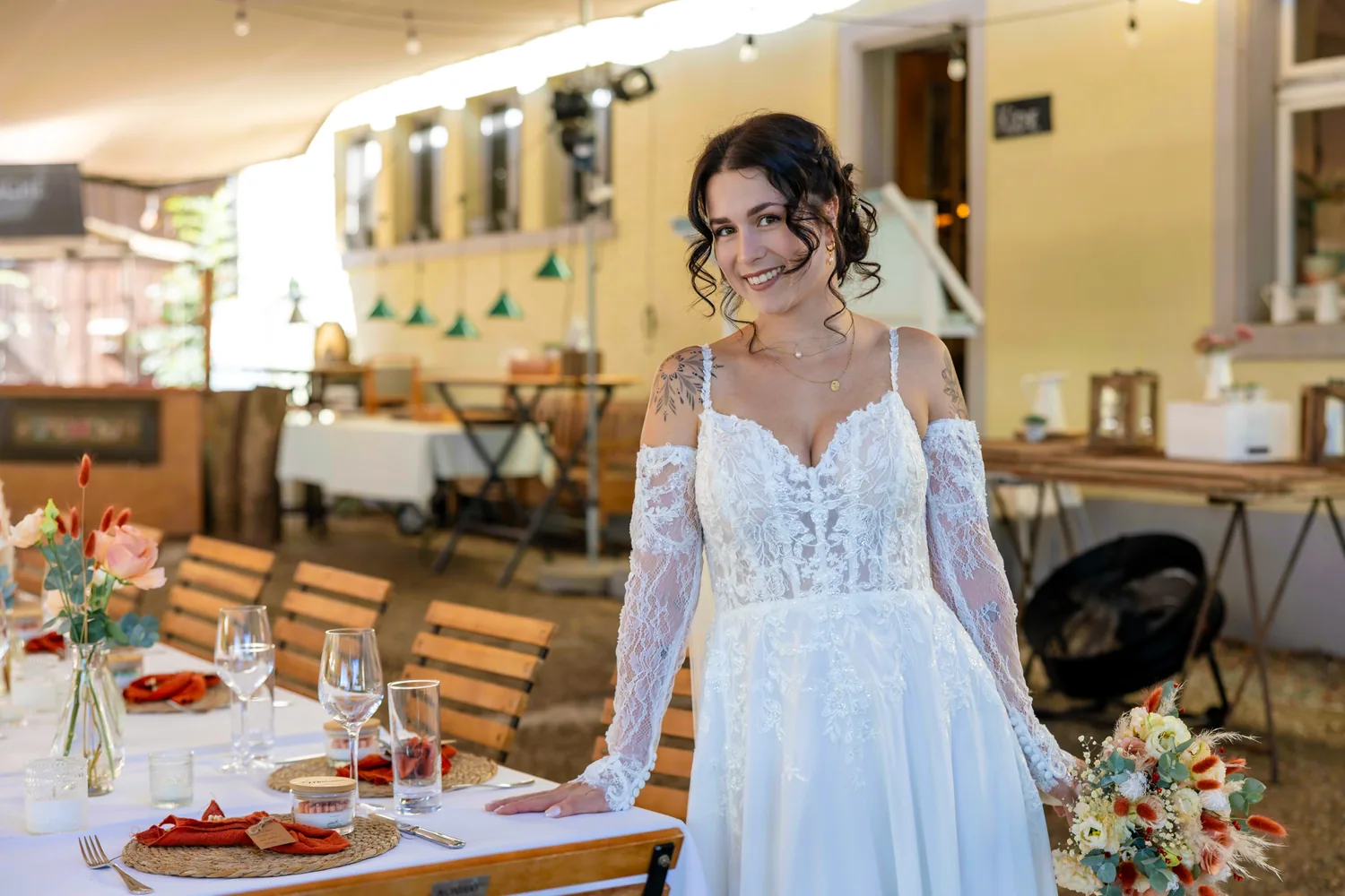 Braut geht im Brautkleid an den gedeckten Tafeln unter dem Zelt vorbei