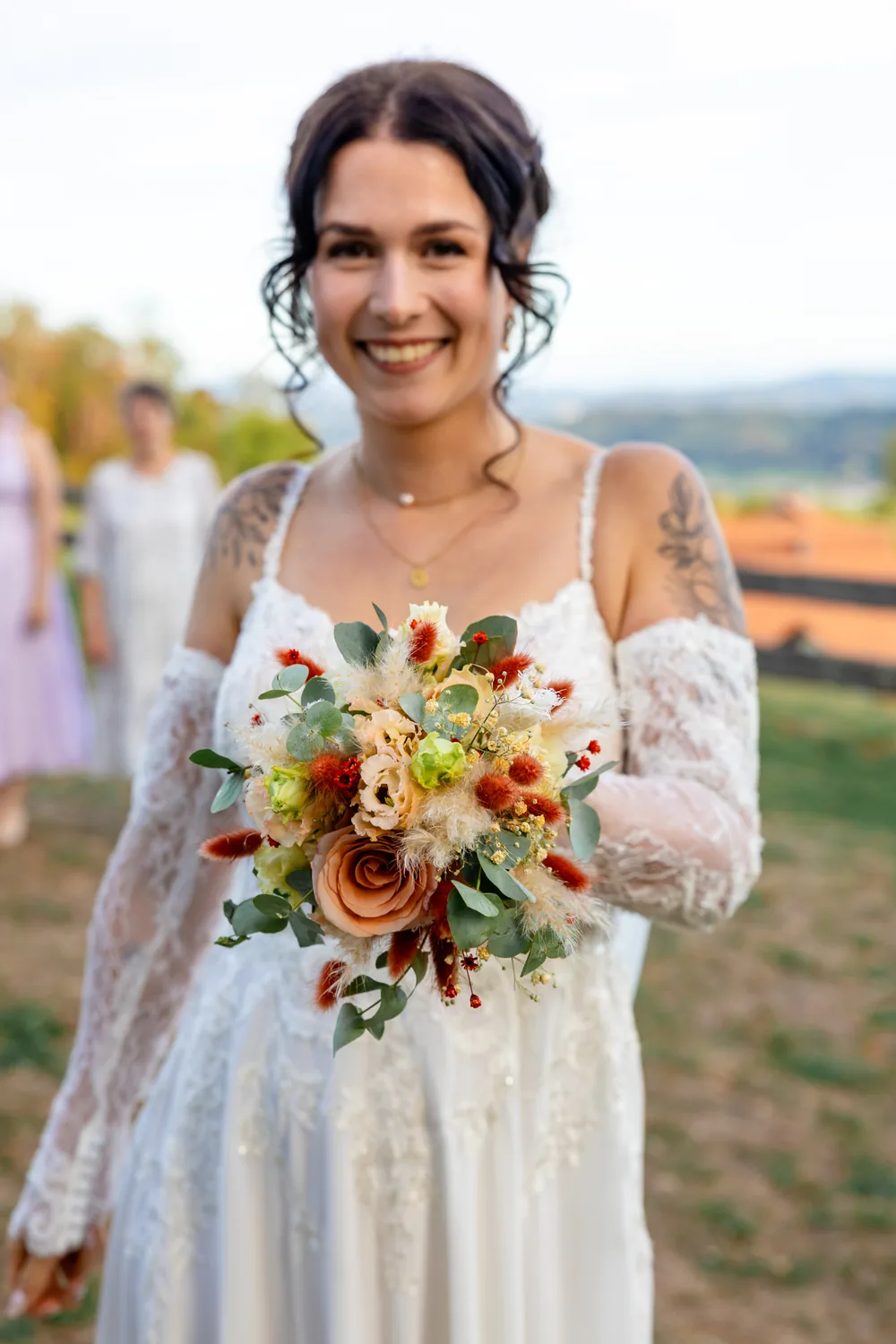 Braut mit herbstlichem Brautstrauss vor der weiten Landschaft