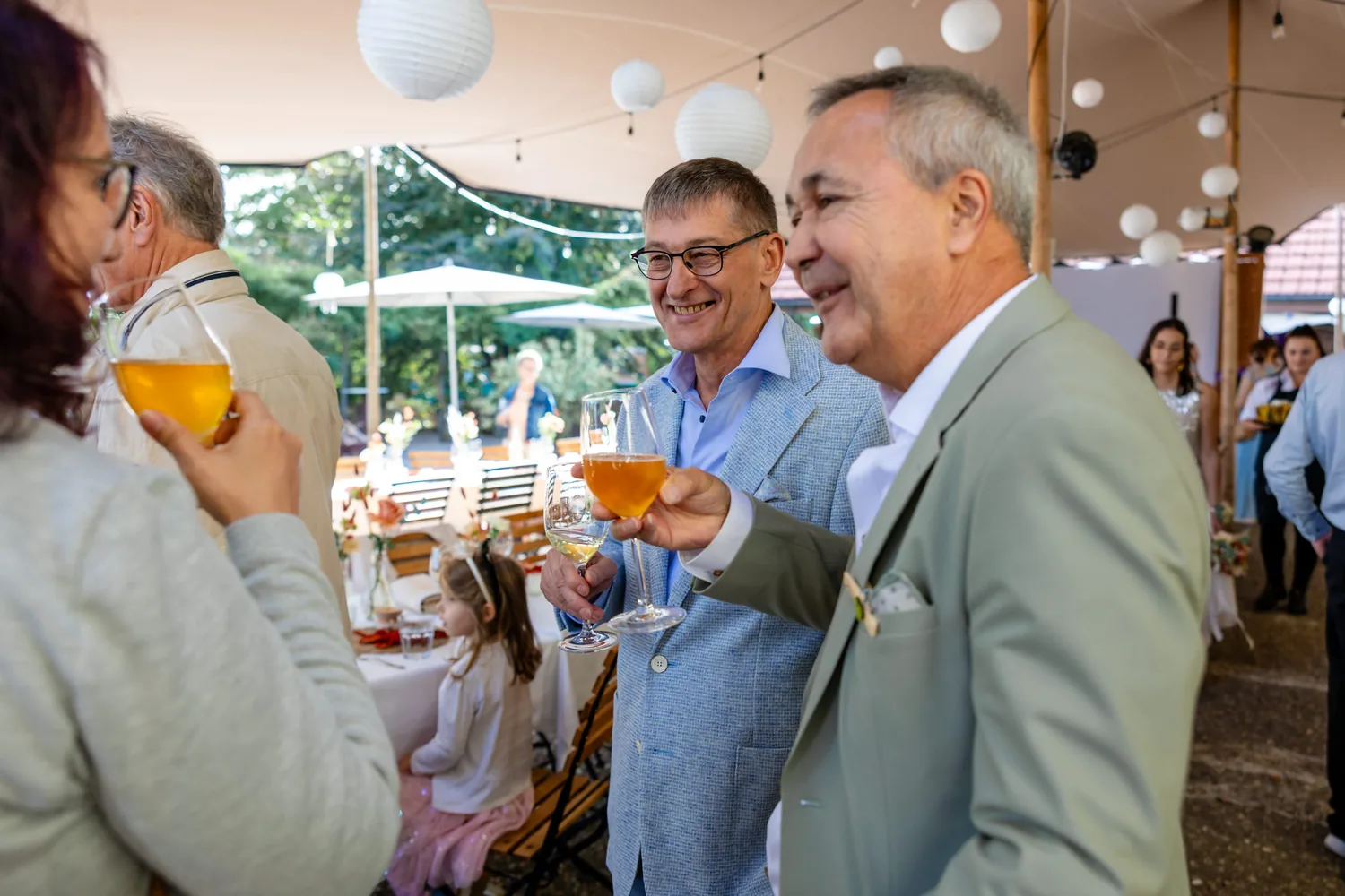 Gäste stossen beim Apéro im Garten mit Gläsern an