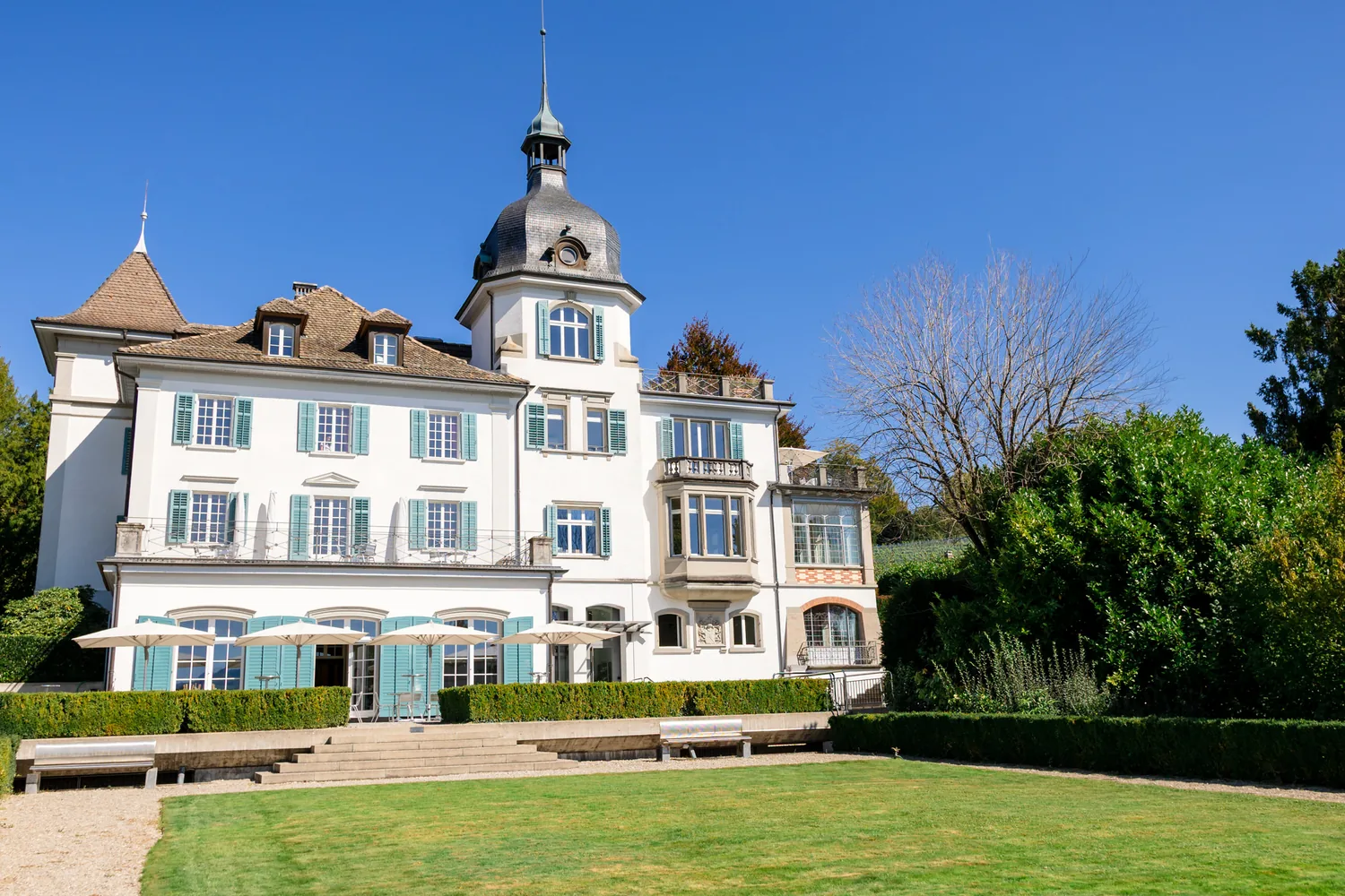 Das Erlengut in Erlenbach: weisses Herrschaftshaus mit Turm, grünen Fensterläden und Rasen davor