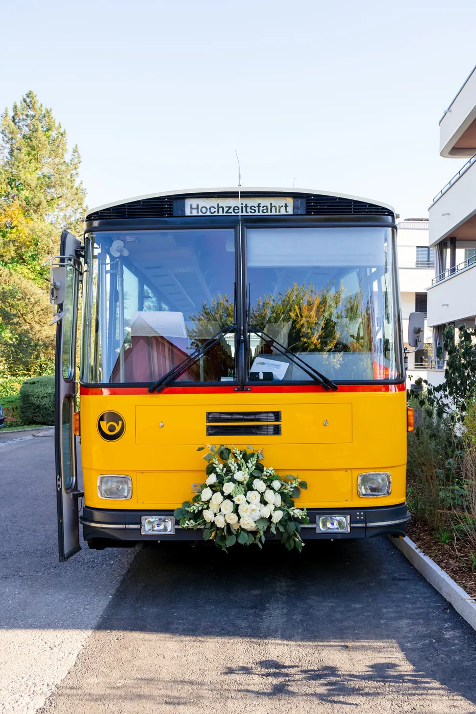 Historisches gelbes Postauto mit Blumenschmuck und Schild Hochzeitsfahrt