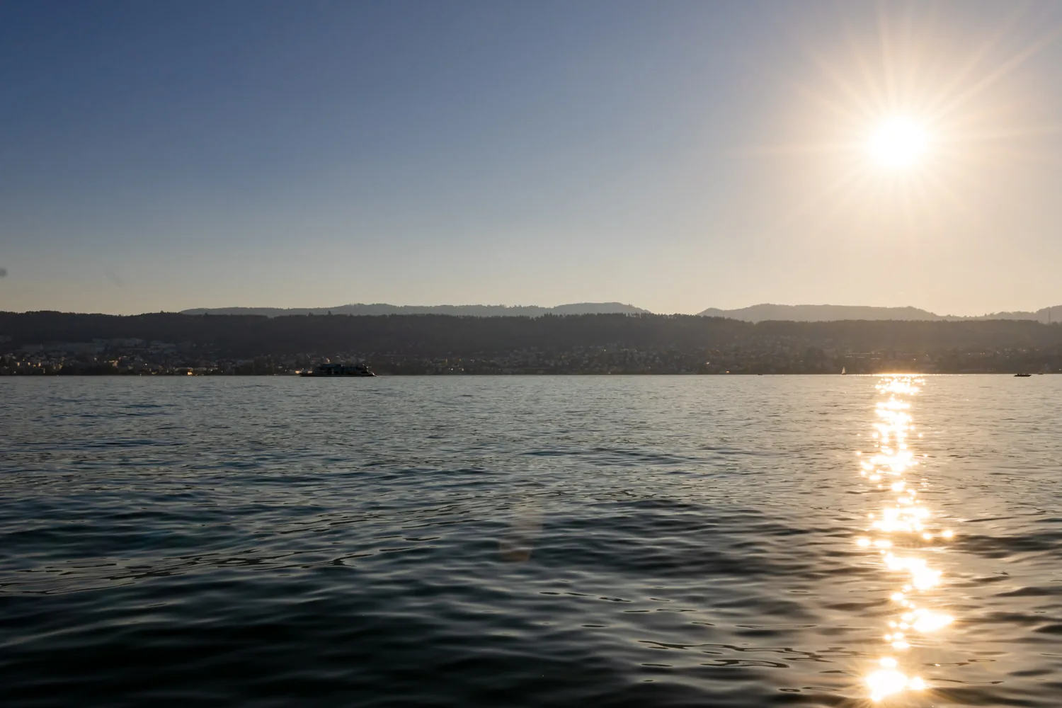 Sonnenuntergang über dem Zürichsee, die Sonne steht tief über dem gegenüberliegenden Ufer
