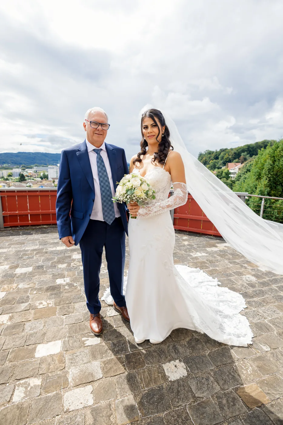 Braut steht mit ihrem Vater auf dem Vorplatz der Schlosskirche, dahinter das Tal