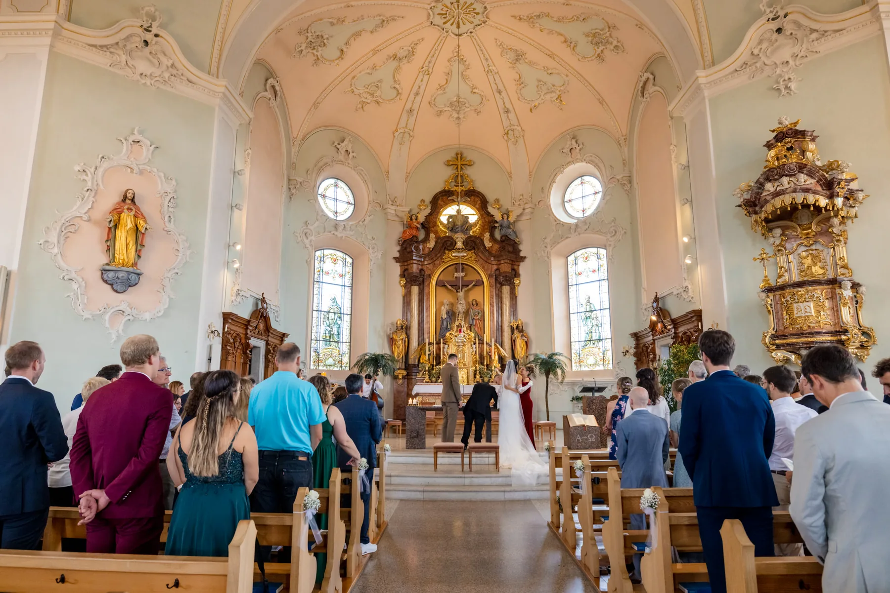 Blick durch die volle Schlosskirche St. Anton zum goldenen Hochaltar während der Trauung