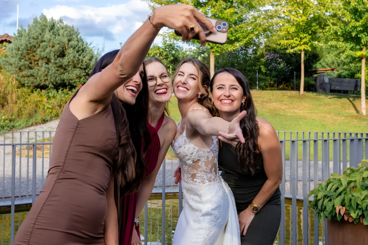 Die Braut macht mit drei Freundinnen ein lachendes Selfie im Garten