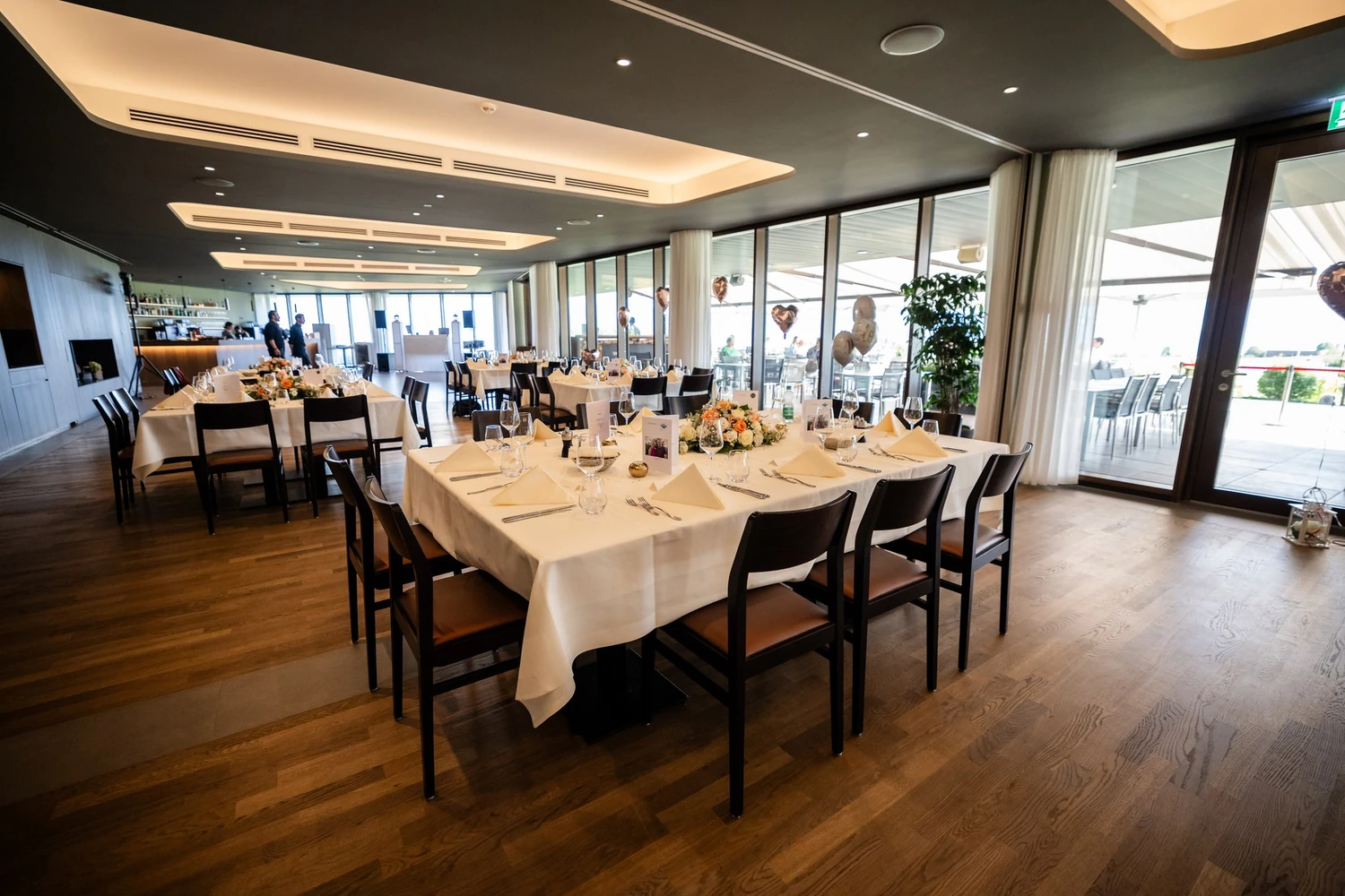 Lange gedeckte Tafel im Restaurant des Gasthaus Badhof, dahinter Fensterfront zur Terrasse