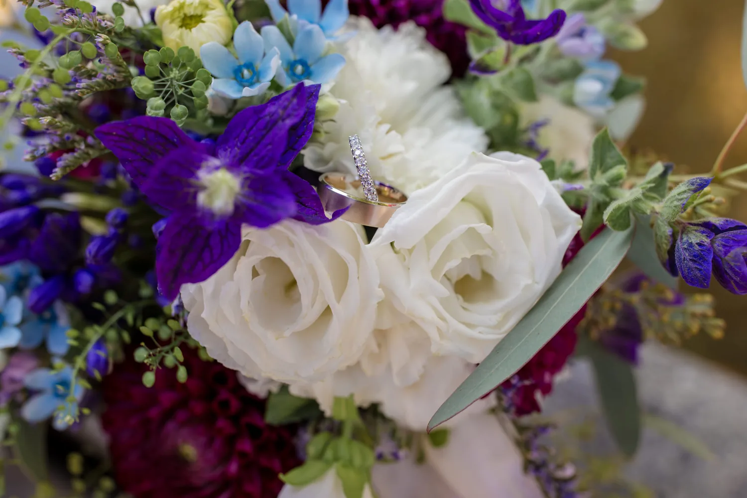 Brautstrauss aus weissen Rosen und blauen Blüten, dazwischen ein Ring