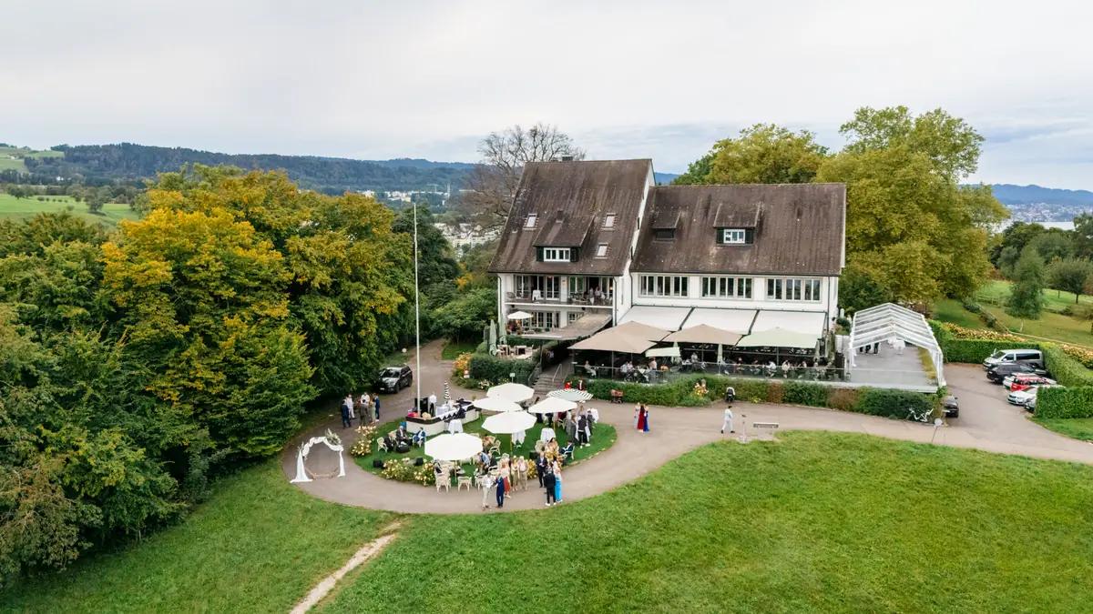 Luftaufnahme des Landgasthofs auf der Halbinsel Au: Terrasse, Apéroschirme auf dem Rundweg und der Blumenbogen auf der Wiese