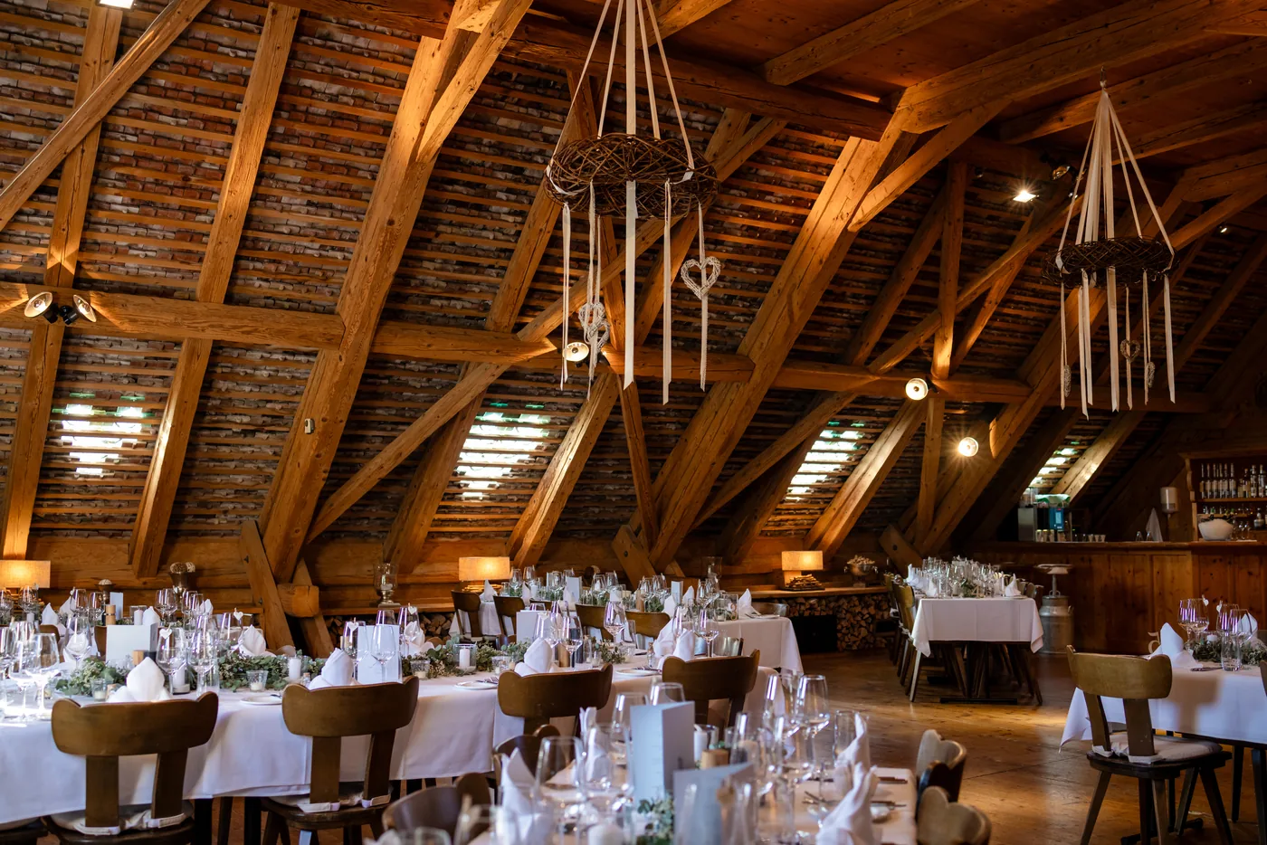 Die alte Schüür mit langen gedeckten Tafeln unter dem offenen Dachstuhl, im Hintergrund die Bar