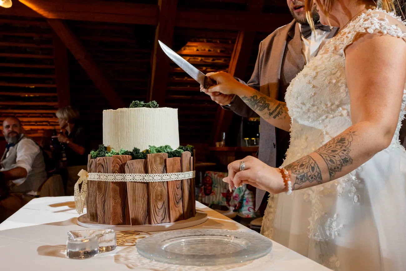 Brautpaar schneidet gemeinsam die zweistöckige Hochzeitstorte an