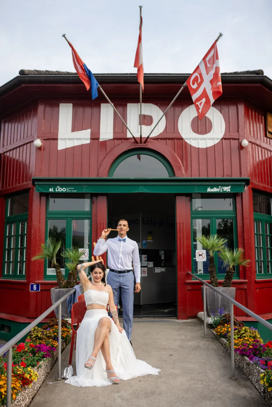 Brautpaar vor dem roten Eingangsgebäude des Lido di Lugano mit der grossen Aufschrift LIDO
