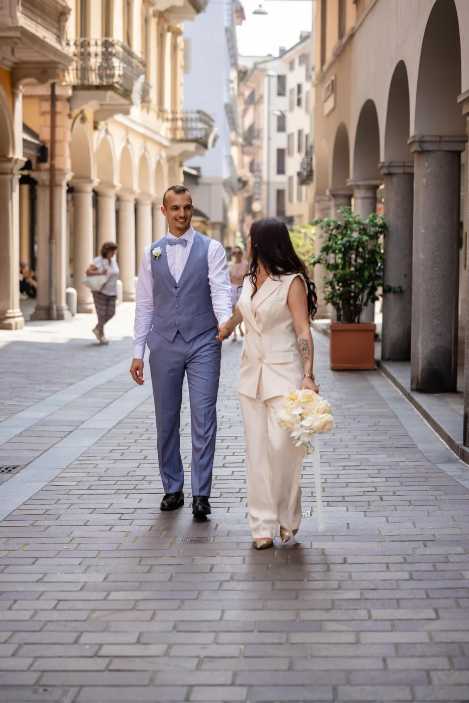 Brautpaar geht Hand in Hand durch eine Gasse mit Arkaden in der Altstadt von Lugano