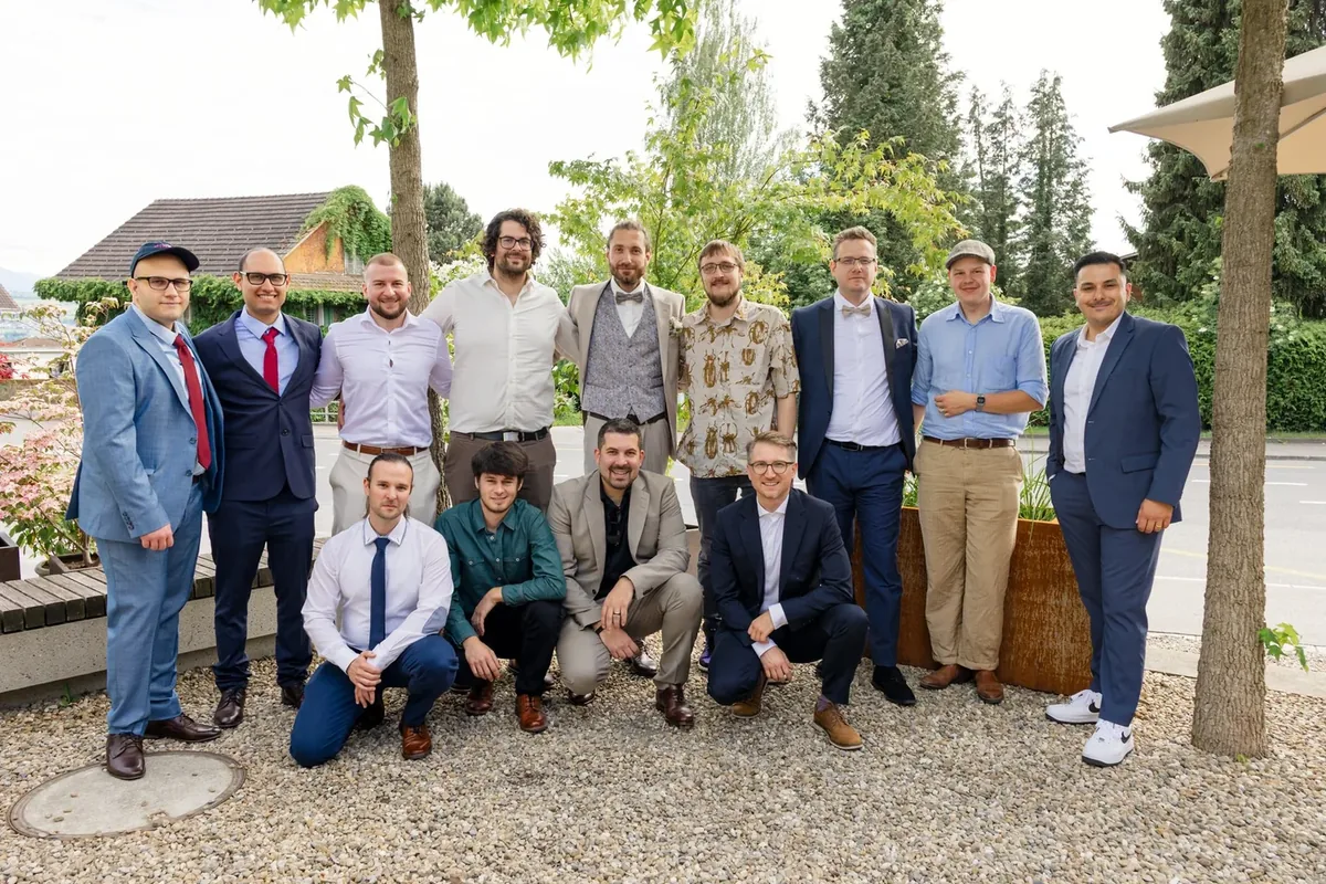 Grössere Gästegruppe posiert auf dem Kiesplatz vor dem Haus