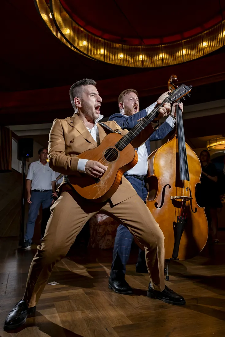 Ein Gitarrist und ein Kontrabassist spielen im Saal und singen mit vollem Einsatz