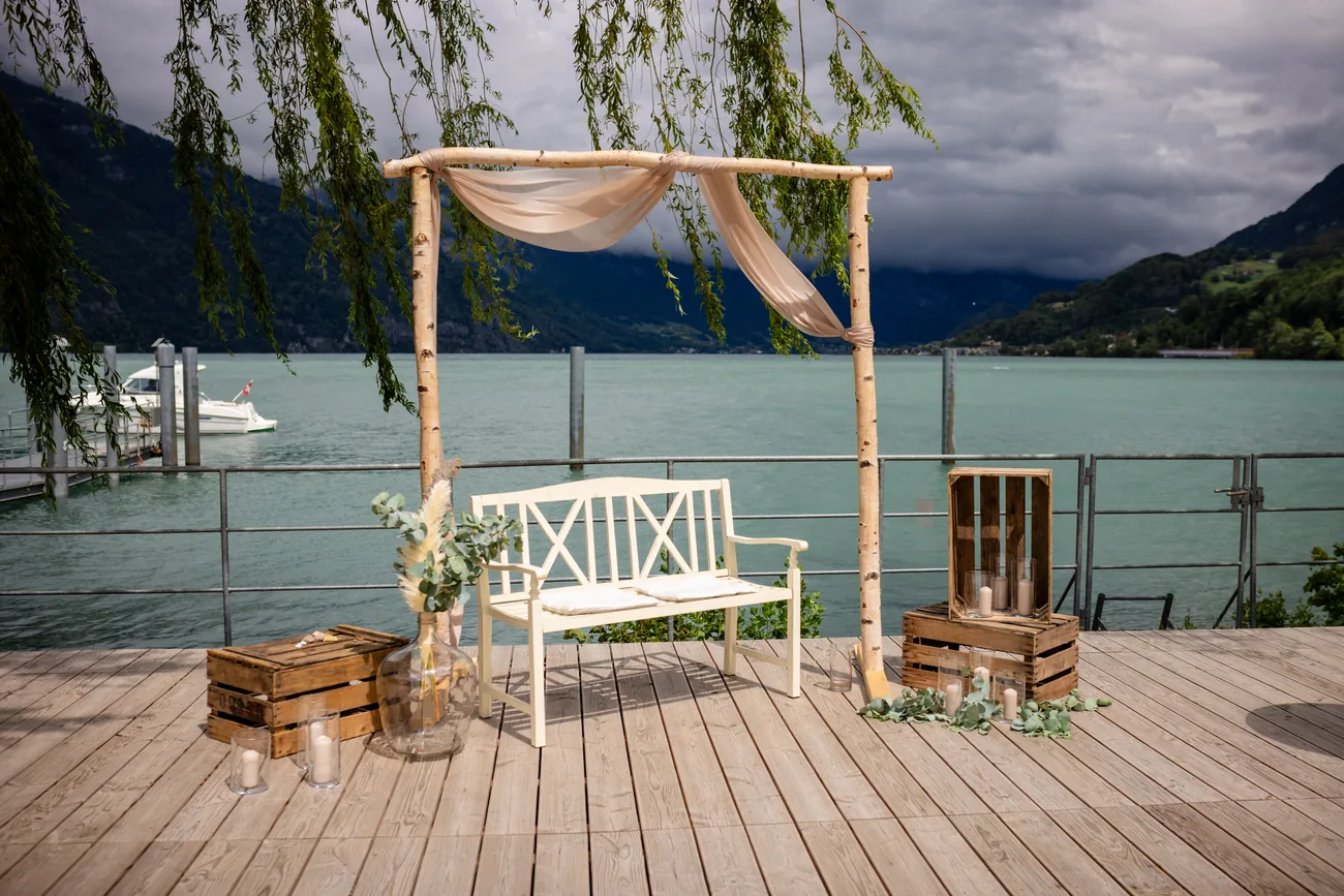 Trauungsbogen aus Birkenstämmen mit Stoffbahn und weisser Bank auf dem Holzdeck am Walensee