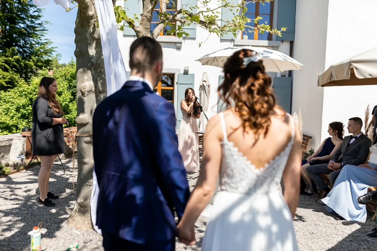 Das Brautpaar geht Hand in Hand auf den Zeremonieplatz zu