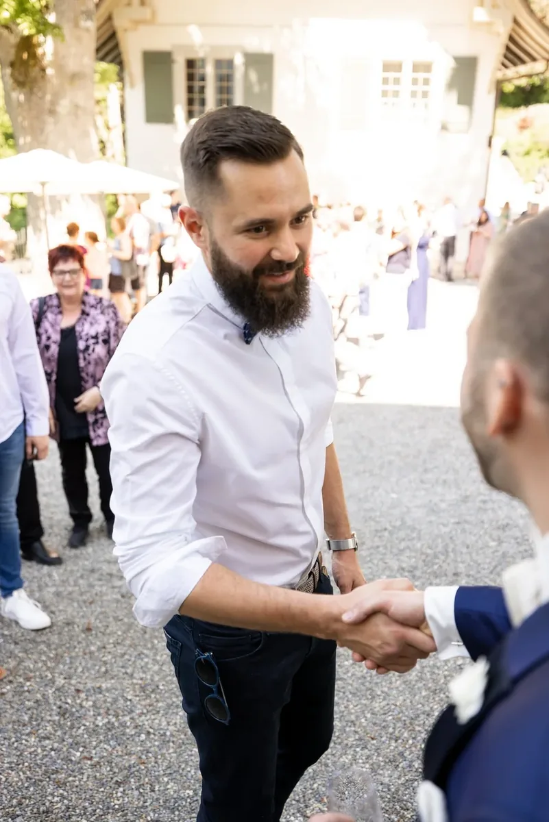 Ein Gast schüttelt dem Bräutigam die Hand
