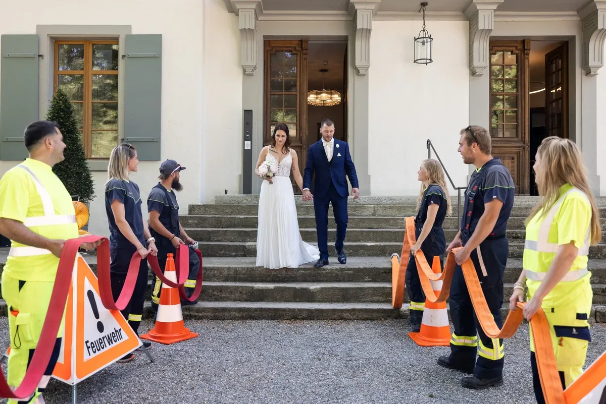 Feuerwehrleute in Warnkleidung bilden ein Spalier vor der Schlosstreppe