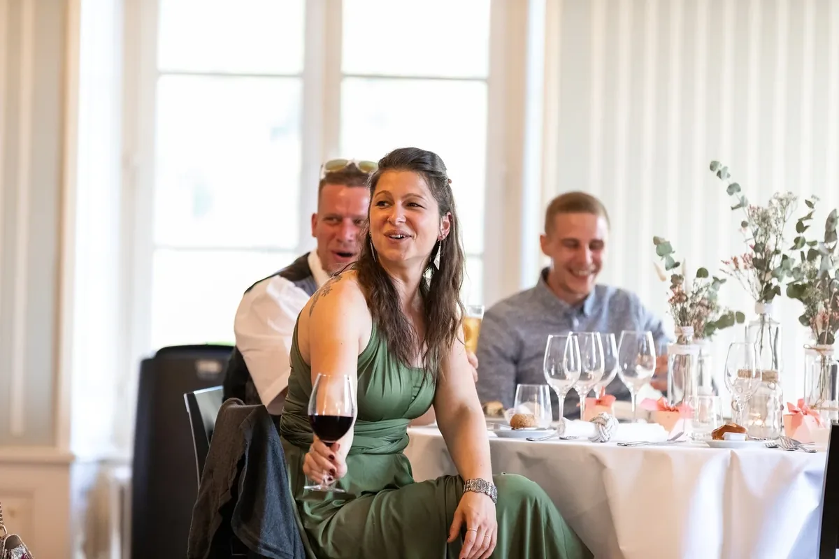 Gäste sitzen und lachen an der gedeckten Tafel