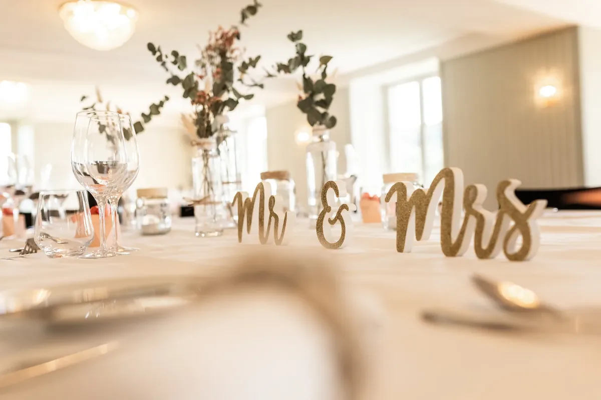 Goldener Holzschriftzug Mr und Mrs auf der gedeckten Tafel