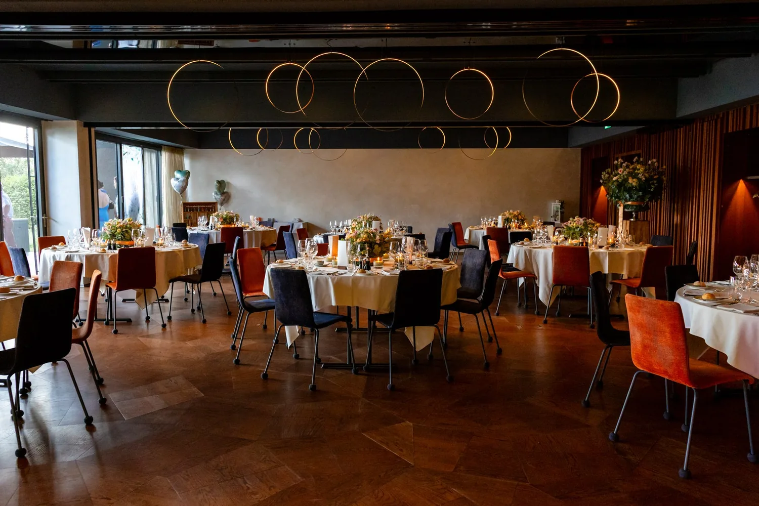 Gedeckte runde Tische im Saal vor dem Dinner, warmes Licht