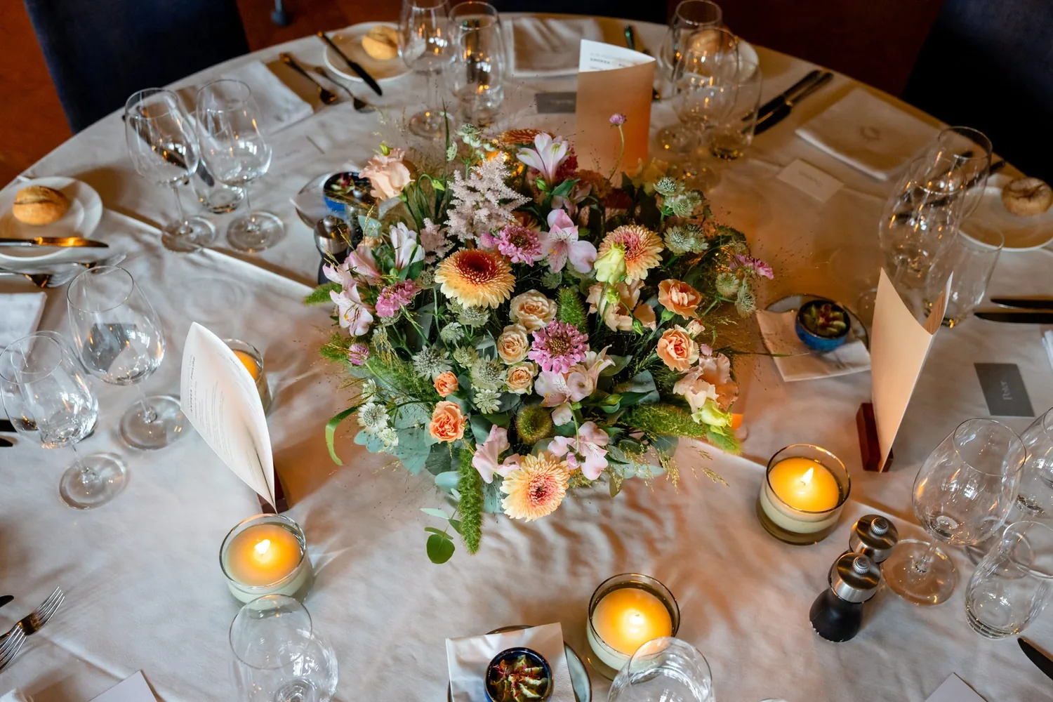 Von oben: gedeckter Tisch mit Blumen, Kerzen und Menükarten