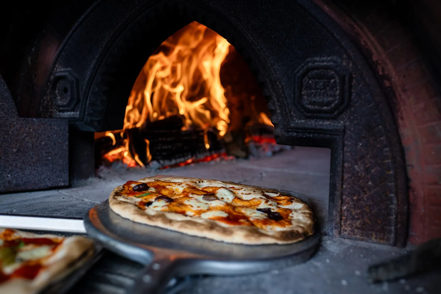 Pizza im brennenden Holzofen im Traumgarten