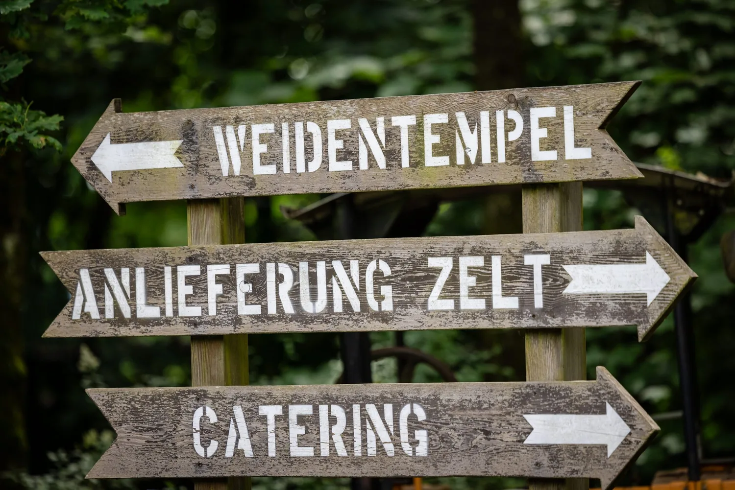 Holzwegweiser mit den Aufschriften Weidentempel, Anlieferung Zelt und Catering