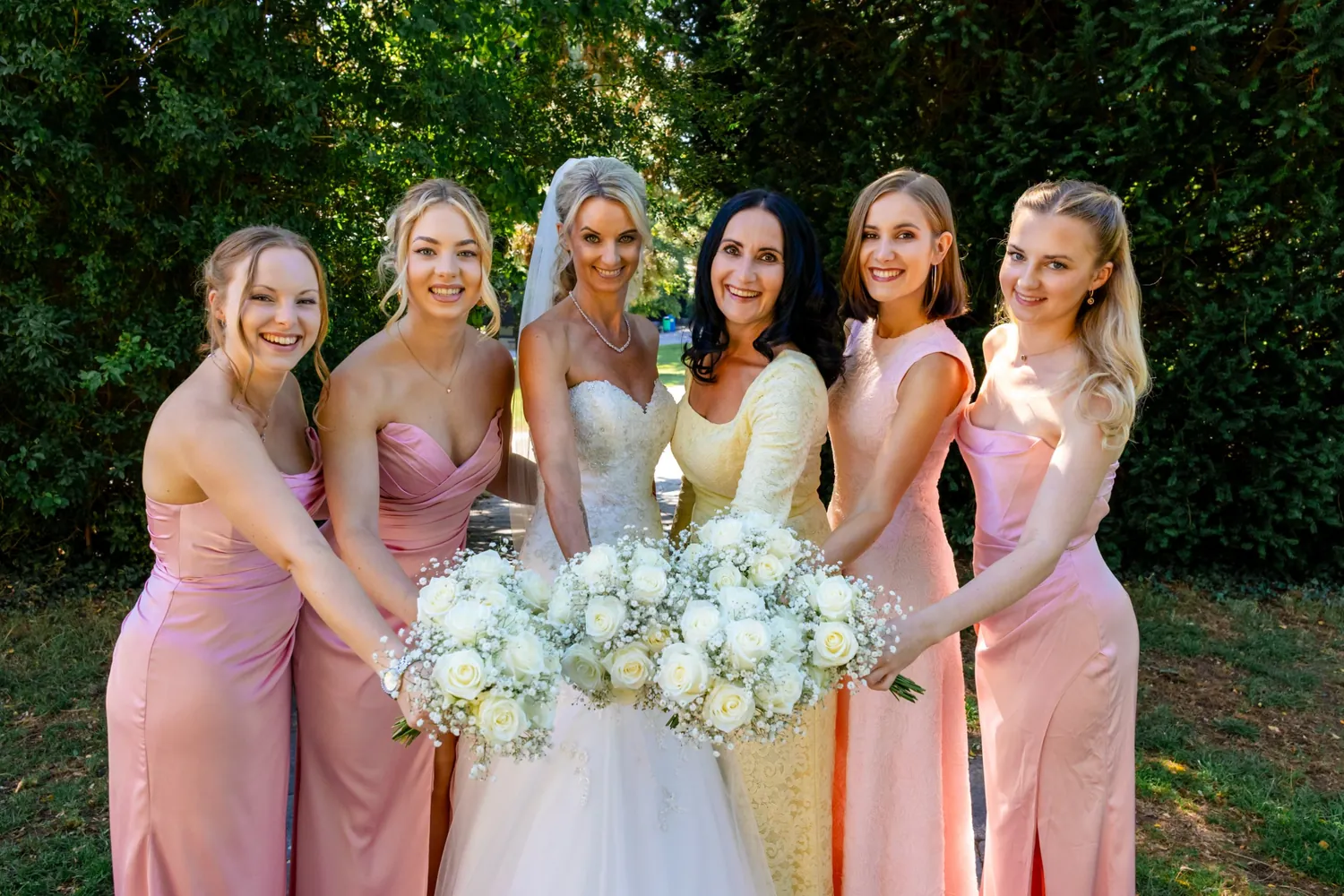 Braut mit Brautjungfern in Rosa aus Satin und einer Frau in Butter-Gelb mit Spitze
