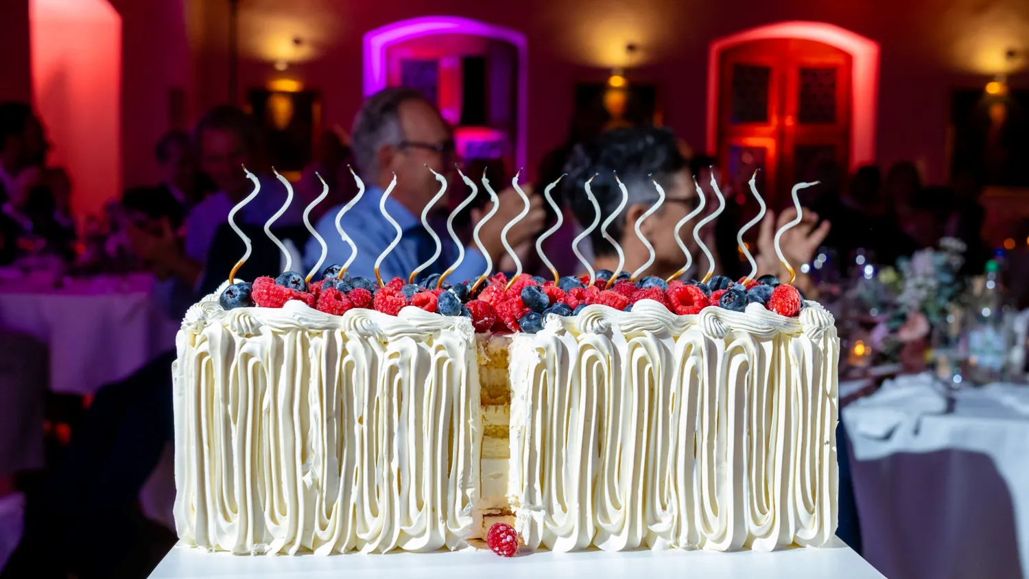 Einstöckige Buttercremetorte mit Beeren und gedrehten Kerzen, angeschnitten