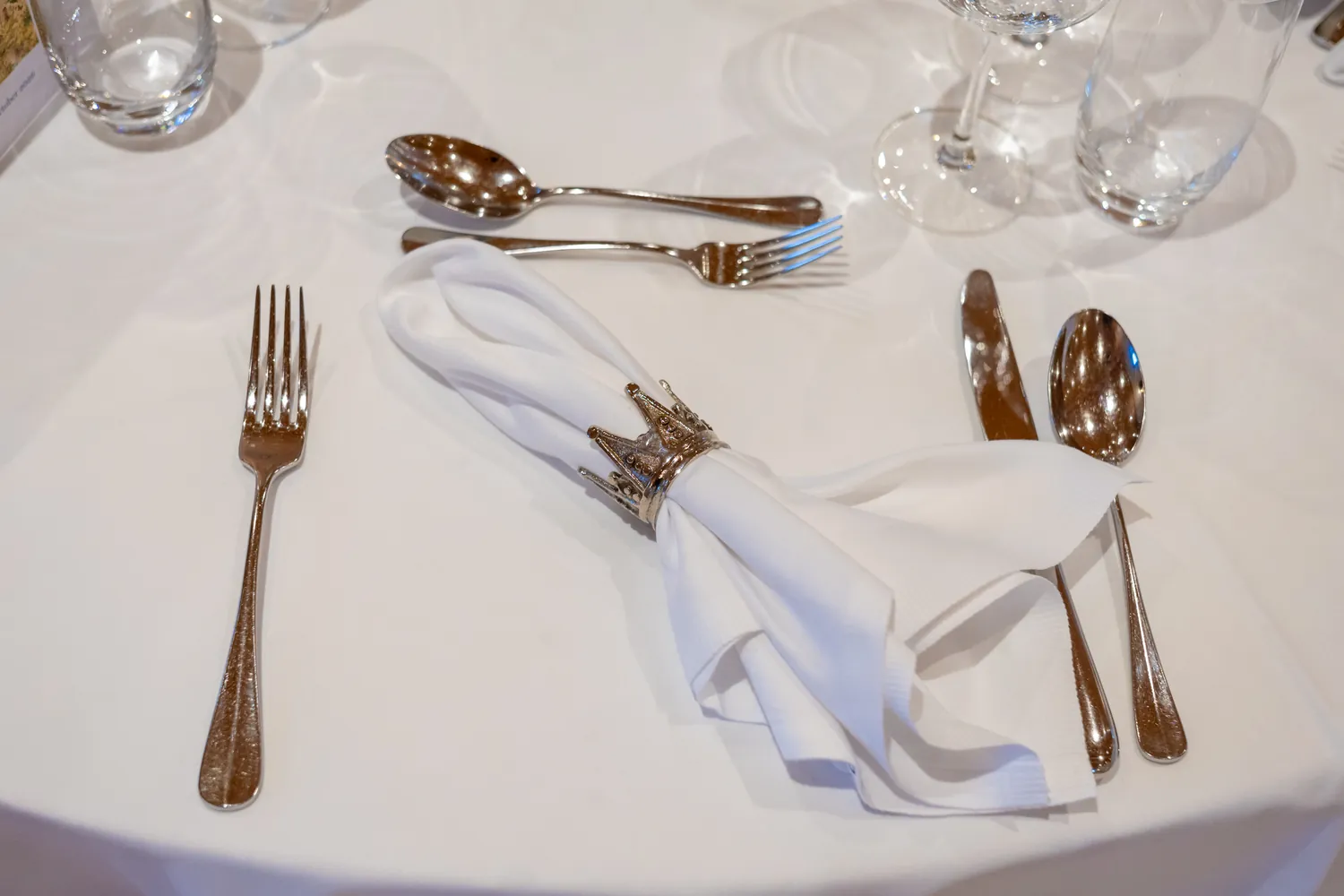 Gedeck mit Silberbesteck und Serviettenring in Kronenform