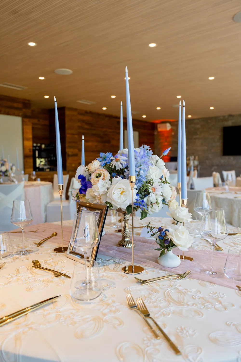 Tisch mit Spitzendecke, puderblauen Kerzen und blauen Blüten