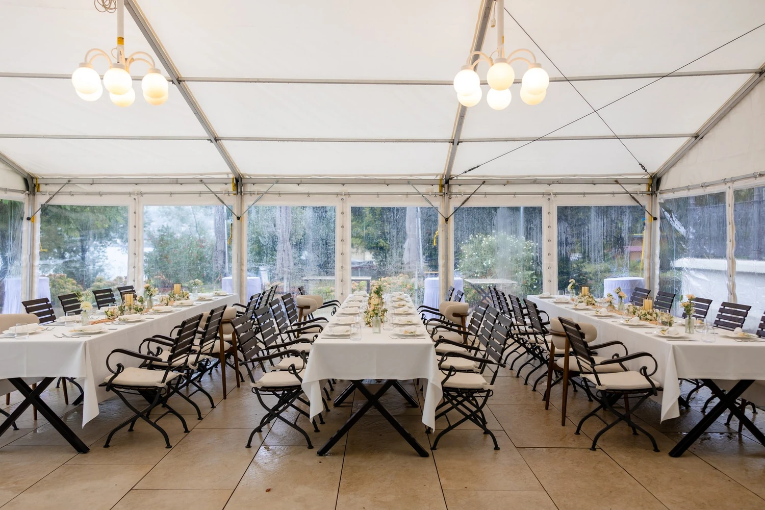 Lange gedeckte Tafeln im Pavillon mit Leuchtern und Blick durch die Seitenwände ins Grüne
