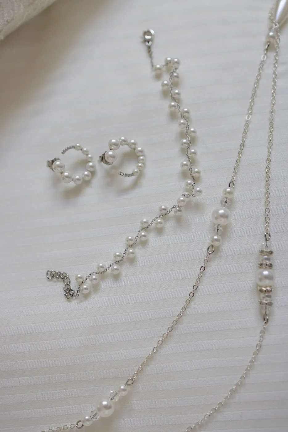 Schmuck, Ohrringe und die Eheringe der Braut auf hellem Untergrund