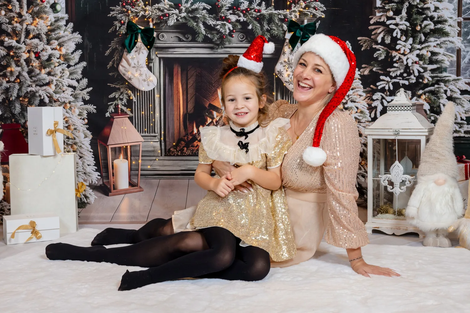 Eine Mutter mit Weihnachtsmütze lacht, ihre Tochter im goldenen Kleid sitzt auf ihrem Schoss