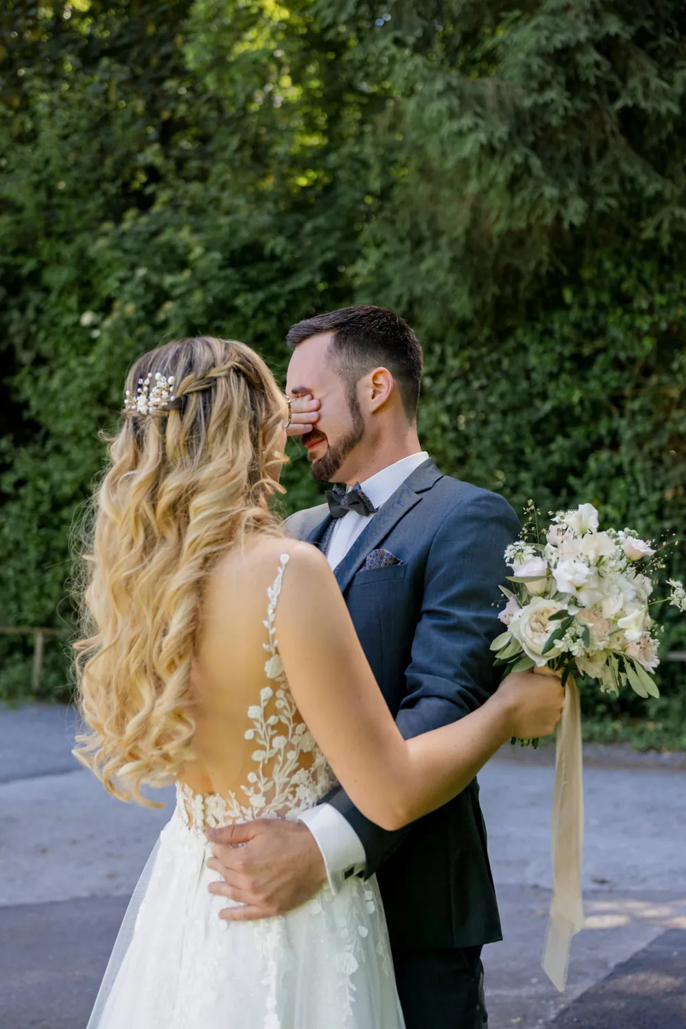 Beim First Look hält sich der Bräutigam gerührt die Hand vor die Augen, die Braut steht mit dem Strauss vor ihm